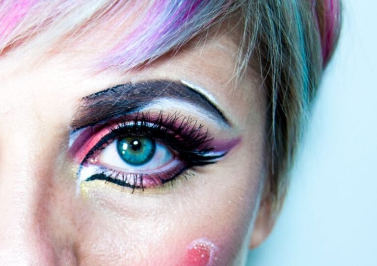artystyczny makijaż na twarzy kobiety, niebieskie usta, dużo kolorowych pasemek we włosach