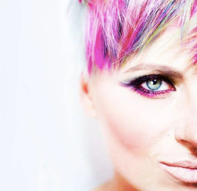 artystyczny kolorowy makijaż na twarzy kobiety i kolorowe, krótko obcięte włosy
